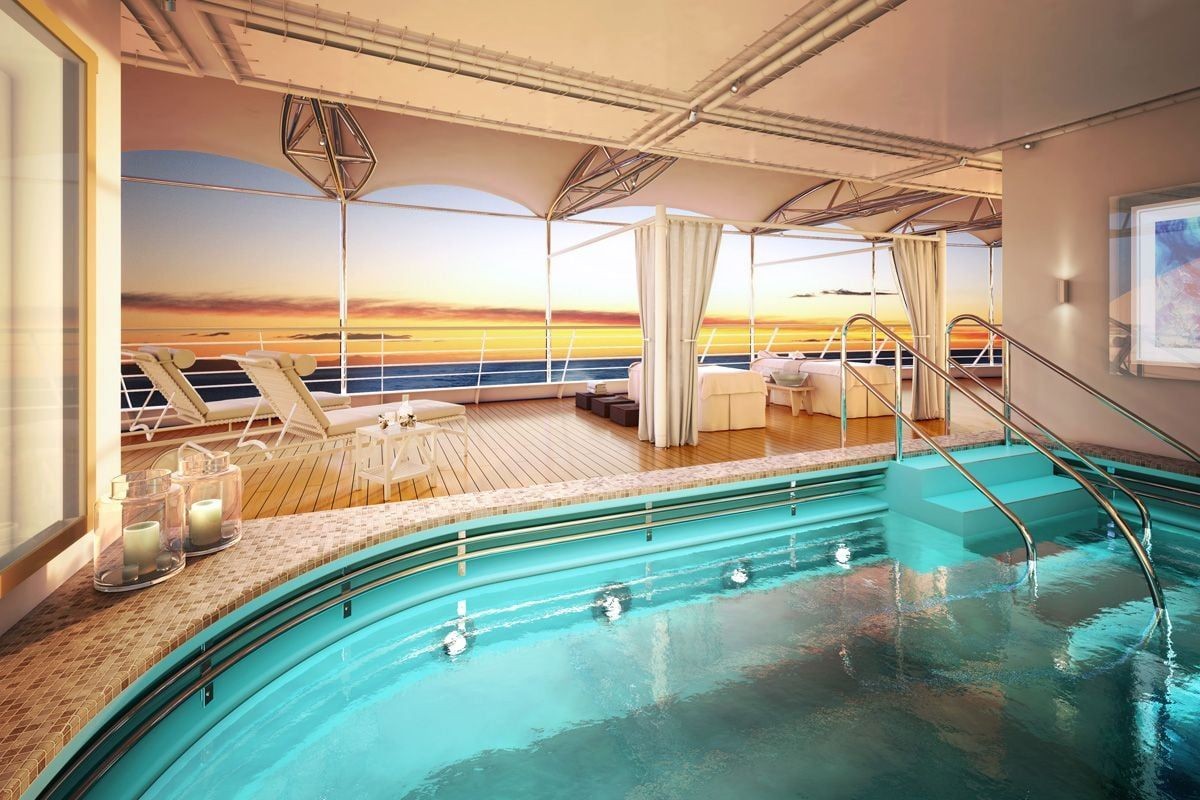 indoor luxury pool on a cruise shit looking out to the deck with sunbeds