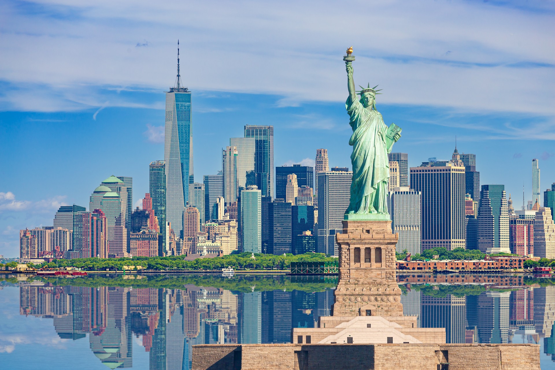 Statue of Liberty and New York City Skyline with Manhattan Financial District, World Trade Center, Empire State Building and Blue Sky.